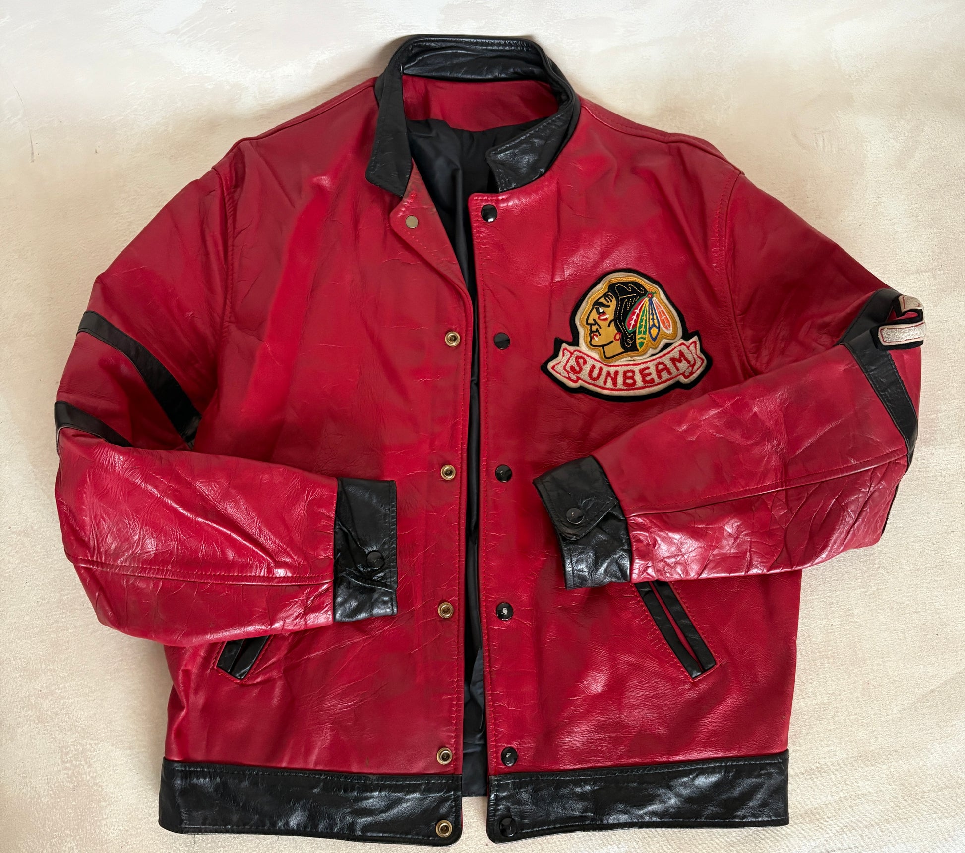 Red leather jacket with black accents and a visible brand logo on a beige background